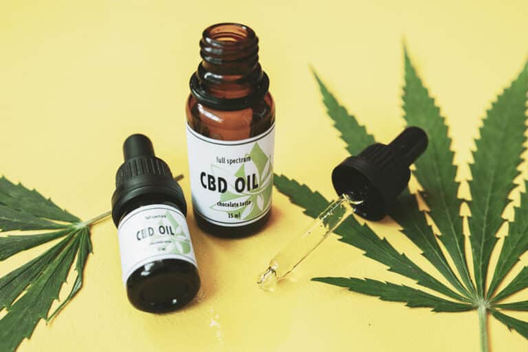Huile de CBD sur une table en bois avec plantes environnantes